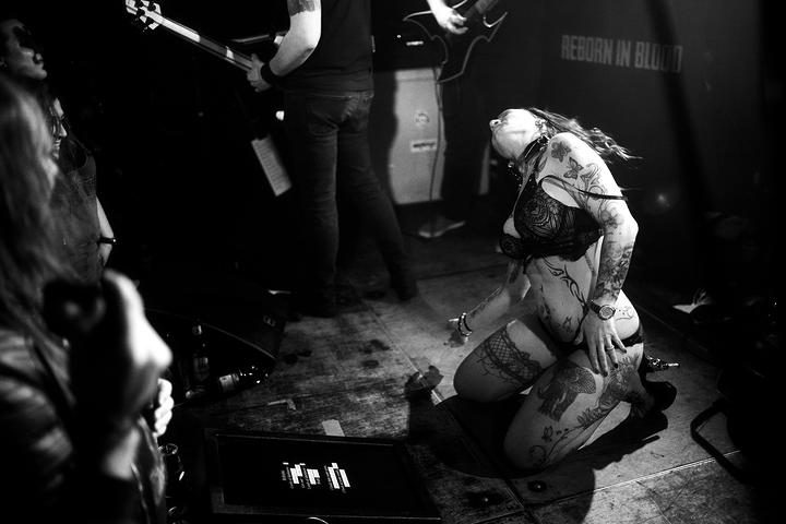 Knieende Stripperin auf der Heavy Metal Bühne.